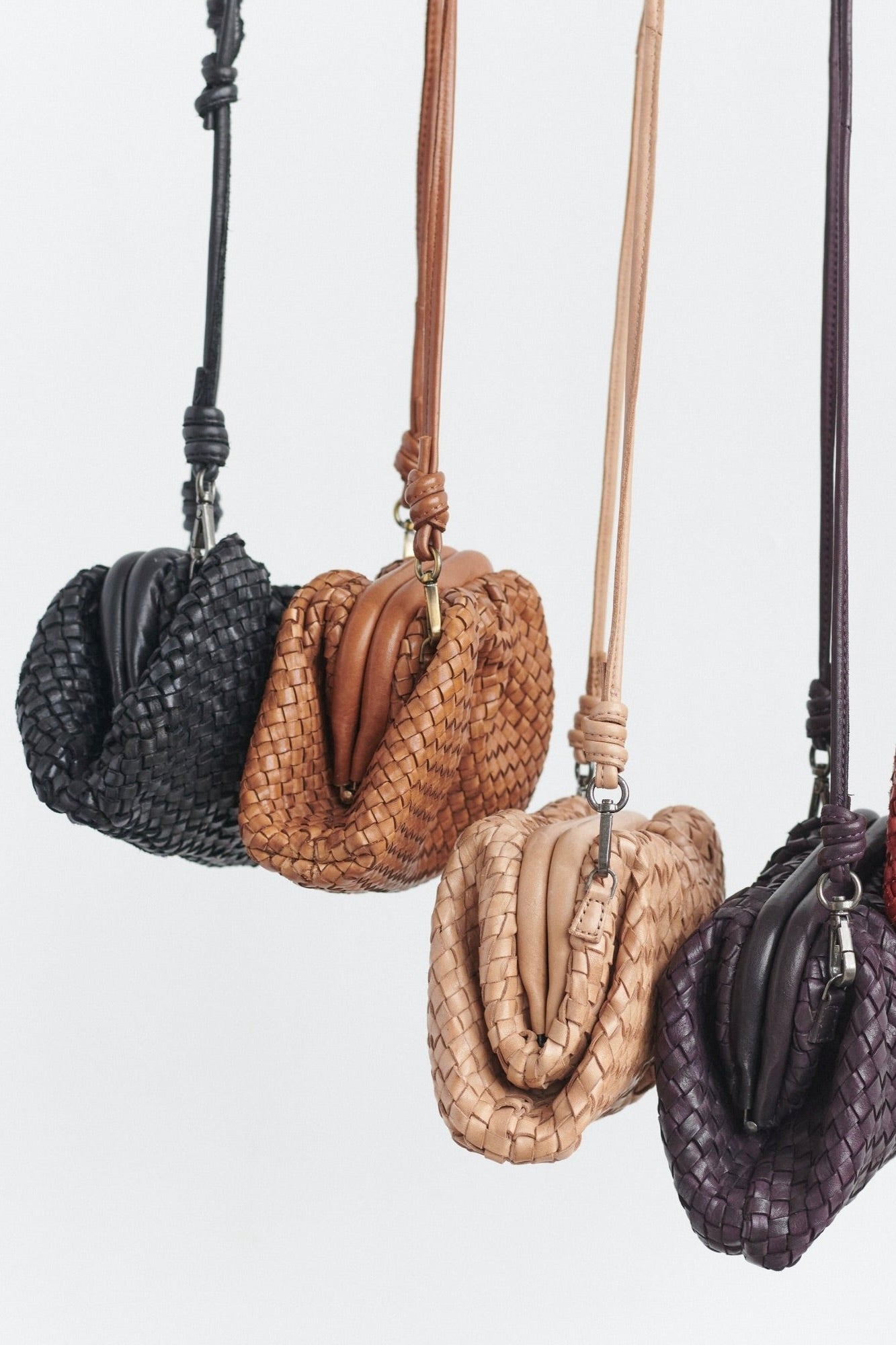 Set of five woven handbags in black, brown, beige, and purple on a light gray background.